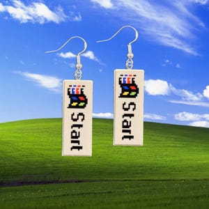 May include: A pair of rectangular earrings with a cream-colored background. Each earring features a pixelated Windows logo in red, blue, yellow, and green, with the word "start" in black. The earrings hang from silver-colored hooks.