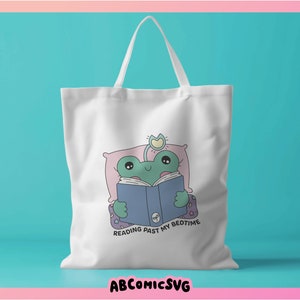 Op de afbeelding: Witte tote bag met een groene kikker die in bed een blauw boek leest. De tekst op de tas is "Reading past my bedtime".