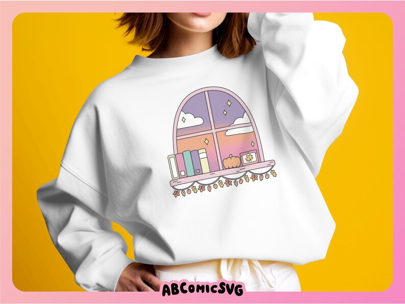 May include: White sweatshirt with a colourful illustration of a window scene. The design includes books, a pumpkin, and fairy lights. The window shows a sunset sky with stars and clouds. The text "ABCOMICSVG" is at the bottom.