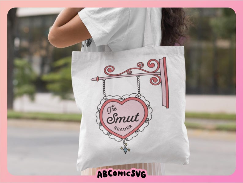 May include: White tote bag with a pink heart-shaped sign that says "The Smut Reader".
