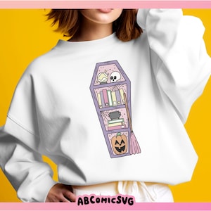 May include: A white sweatshirt featuring a purple coffin-shaped bookshelf design. The bookshelf is filled with books, a cauldron, a broom, a skull, a spiderweb, and a jack-o'-lantern.