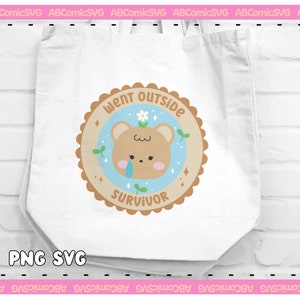 May include: A white tote bag with a brown and blue circular design featuring a cartoon bear with a tear, a flower, and the text "Went Outside Survivor".