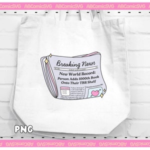 Puede incluir: Una bolsa de tela blanca con una ilustraci&oacute;n rosa y morada de un titular de peri&oacute;dico que dice "Breaking News: New World Record: Person Adds 1000th Book Onto Their TBR Shelf".