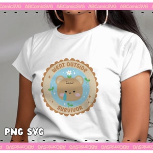 May include: A white t-shirt with a brown and blue graphic of a cartoon bear with a tear on its cheek. The graphic is surrounded by a brown circle with the text "Went Outside Survivor" in white.