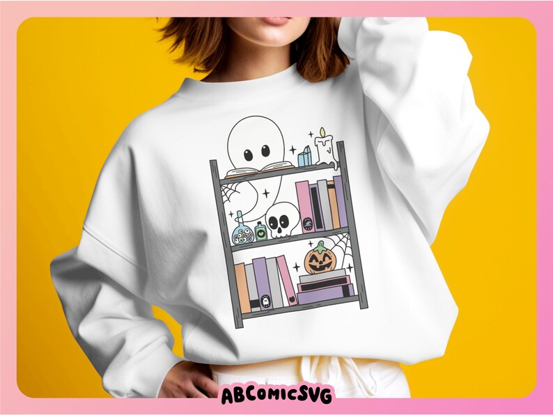 May include: A white sweatshirt featuring a graphic of a ghost reading a book on a bookshelf with Halloween decorations. The decorations include a pumpkin, a skull, a candle, and potion bottles.
