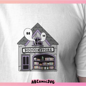 Pu&ograve; includere: Una maglietta bianca con un'illustrazione viola e grigia di una libreria spettrale con il testo "Booookstore" sopra la porta. Due fantasmi galleggiano sopra l'edificio.