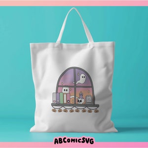 May include: White tote bag with a Halloween illustration. The design depicts a window with ghosts, books, a skull, and pumpkins. The text "ABCOMICSVG" is at the bottom of the bag.
