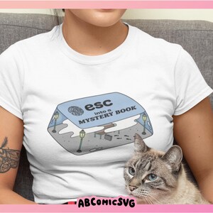 May include: White t-shirt with a blue and white illustration of a book with the text "esc into a mystery book".