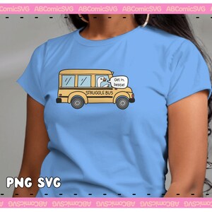 Pode incluir: Uma camiseta azul clara com uma ilustra&ccedil;&atilde;o de desenho animado de um &ocirc;nibus escolar amarelo com um ganso dirigindo. O &ocirc;nibus diz "Struggle Bus" e o ganso diz "Get in, bestie!"