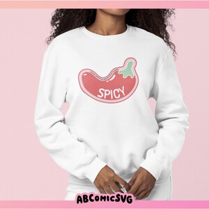 May include: White sweatshirt with a red and green chili pepper graphic and the word "SPICY" in pink lettering.
