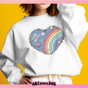 May include: White sweatshirt with a rainbow and planets design in a heart shape. The design says "safe space" in a handwritten font.