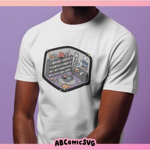 May include: White t-shirt with a cartoon illustration of a bookshelf filled with books, a couch, and a coffee table with a plant on it. The illustration is in a light purple, pink, and blue color scheme.
