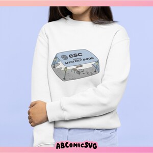 May include: White sweatshirt with a graphic of a blue box with the text "esc into a MYSTERY BOOK" on it.