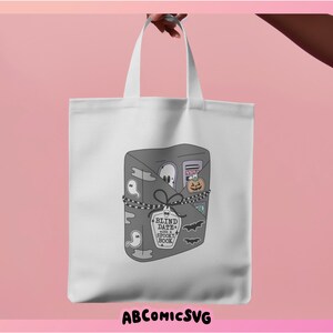 May include: A white tote bag with a gray and black illustration of a book with the text "Blind Date with a Spooky Book" on a tag. The book is filled with spooky Halloween items like ghosts, bats, and a pumpkin.
