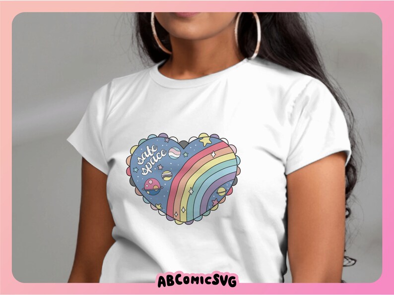 May include: White t-shirt with a rainbow heart design and the text "safe space" in blue lettering. The heart design includes stars, planets, and a rainbow.