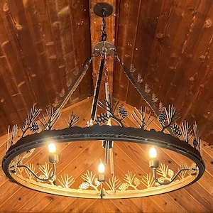 May include: A round, black metal chandelier with a rustic design featuring pine tree silhouettes. The chandelier has four light bulbs and is hanging from a wooden ceiling.