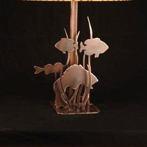 May include: A table lamp base made of metal with a silhouette of fish and plants. The base is a dark brown color.