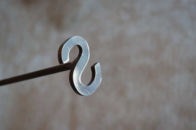 May include: A metal fireplace poker with a decorative S-shaped handle.