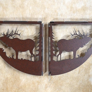 May include: Two metal wall shelf brackets in the shape of an elk silhouette. The brackets are rusty brown and have a rustic look.