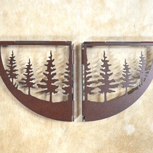 May include: Two rust-colored metal shelf brackets shaped like half circles with a silhouette of pine trees inside.