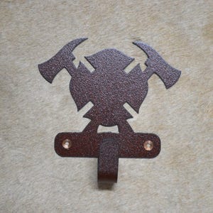 May include: A brown metal firefighter coat hook with a crossed axes and fire hydrant design.