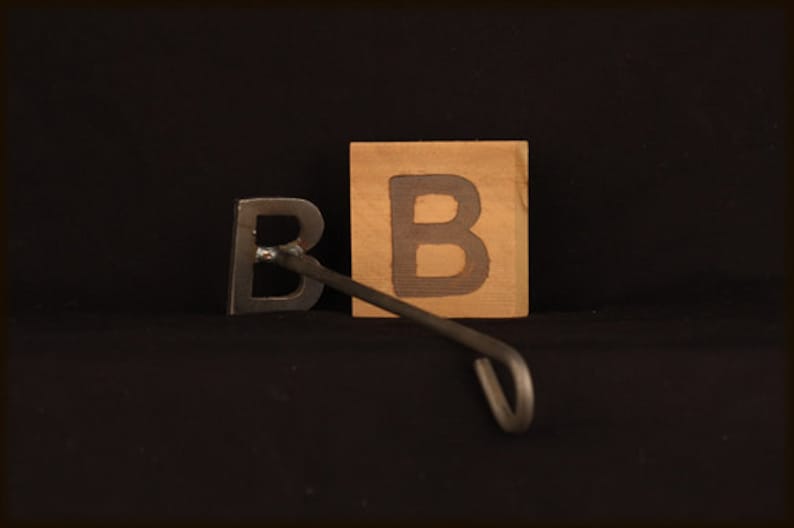 May include: A metal branding iron shaped like the letter "B" with a wooden block with the letter "B" on it.