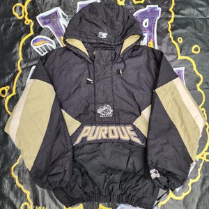 May include: Black and gold hooded jacket with the word "PURDUE" in a bold, white font. The jacket has a zip closure and a drawstring hood. The jacket is made by Starter.