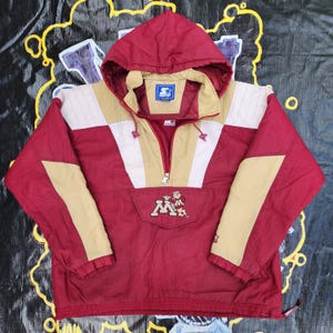 May include: Maroon and gold Starter pullover jacket with a hood. The jacket features a zipper closure, a front pocket with the Minnesota logo, and the Starter logo on the collar. The jacket has gold and white accents.