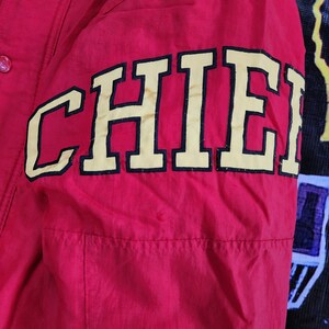 May include: Red jacket with a black and yellow "CHIEFS" embroidered on the sleeve.