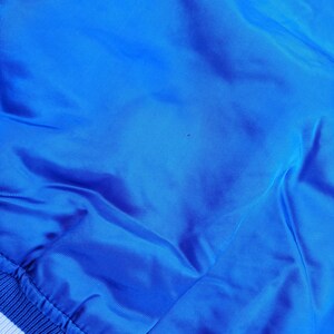 May include: A blue satin bomber jacket with white ribbed trim around the bottom and cuffs.