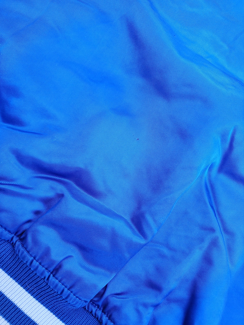 May include: A blue satin bomber jacket with white ribbed trim around the bottom and cuffs.