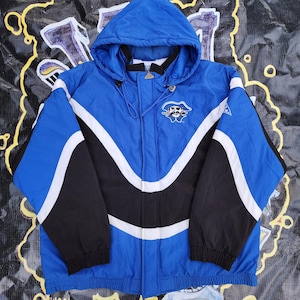May include: A blue, black, and white hooded jacket with a logo on the chest. The jacket has a zipper closure and a drawstring hood. The sleeves are black, and the body is blue with white accents. The jacket is made of a lightweight material.