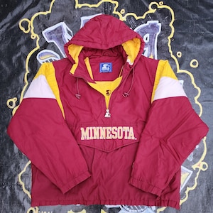 May include: Maroon and gold Starter anorak jacket with the word "MINNESOTA" across the front. The jacket has a hood, a half-zip closure, and white accents on the sleeves. The Starter logo is visible on the chest.