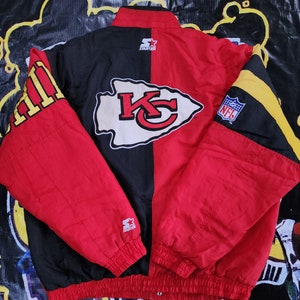 May include: A red and black Starter brand jacket with the Kansas City Chiefs logo on the back. The jacket has a yellow and black stripe on the right sleeve and the NFL logo on the left sleeve.