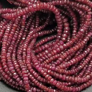 May include: A strand of deep red ruby beads, each bead is faceted and has a slightly irregular shape. The beads are strung on a thin cord and are ready to be used for jewelry making.