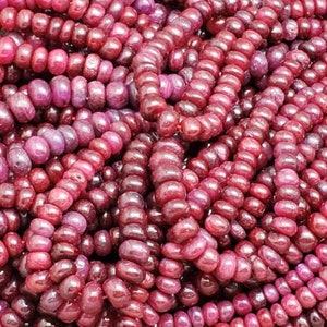 May include: A close-up of a pile of ruby red gemstone beads. The beads are smooth and round, and they are all about the same size.