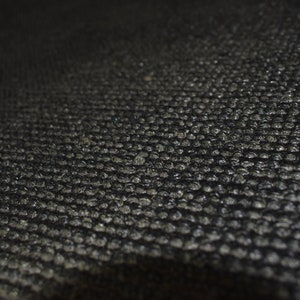 Peut inclure: Gros plan sur un tissu textur&eacute; noir avec un motif en grille. Le tissu a une finition l&eacute;g&egrave;rement brillante.