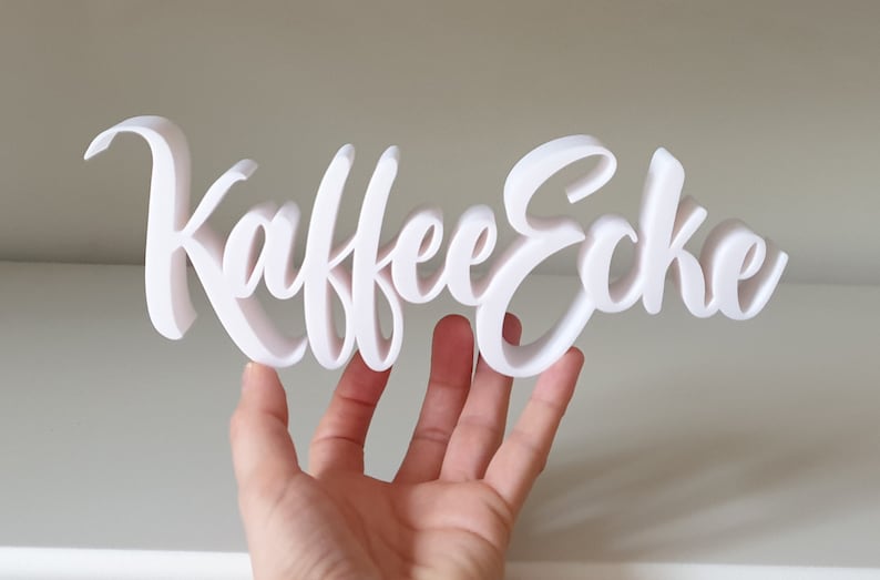 May include: White 3D sign that reads "Kaffee Ecke" in a cursive font.