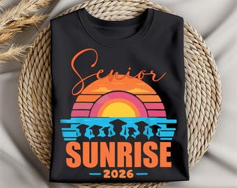 May include: Black t-shirt with a colorful graphic design. The design features the word "Senior" in orange script above a sunset scene with the word "Sunrise" in orange block letters and the year "2026".