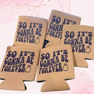 May include: A collection of beige can coolers with the text "SO IT'S GONNA BE FOREVER" in dark blue, along with a ring graphic. The coolers are designed to hold beverage cans and bottles.