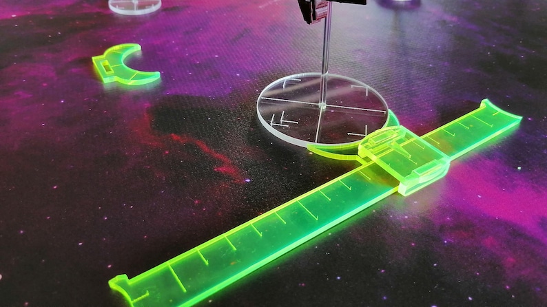 May include: A green plastic ruler with a clear plastic circle in the center. The ruler is marked with measurements and has a clear plastic handle. The circle has a crosshair in the center.