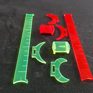 May include: A set of green and red plastic rulers and protractors. The rulers are marked with inches and the protractors are marked with degrees.