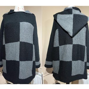 Könnte beinhalten: Ein schwarzer und grauer Kapuzenpullover mit einem karierten Muster. Der Pullover hat eine große Kapuze und lange Ärmel.