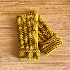 May include: A pair of mustard yellow knitted fingerless gloves with a textured pattern.