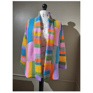 May include: A colorful striped cardigan with a long, open front. The cardigan is made of a soft, knitted fabric and features a variety of colors, including pink, blue, green, yellow, and orange.