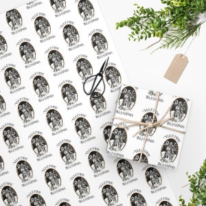 May include: White wrapping paper with a repeating pattern of black and gold illustrations of a couple of figures standing in a snowy forest with the text "Yuletide Blessings".