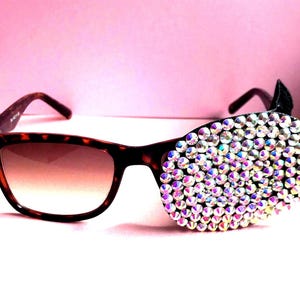 May include: Tortoiseshell sunglasses with one lens covered in iridescent rhinestones.