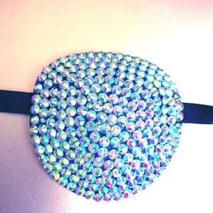May include: A blue eye patch covered in iridescent rhinestones.