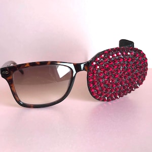 May include: Tortoiseshell sunglasses with a red rhinestone eye patch.