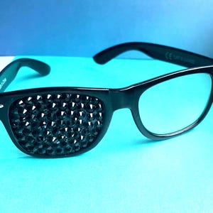 May include: Black sunglasses with one lens covered in black rhinestones. The sunglasses have a black frame and clear lenses.